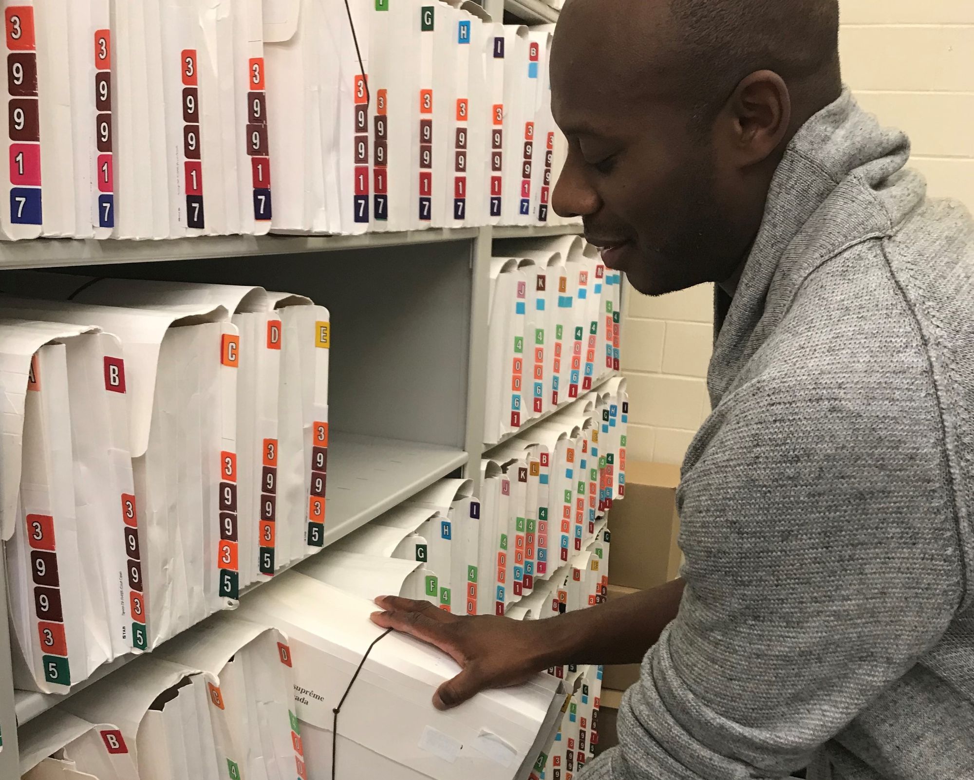 An employee in front of a shelf full of files