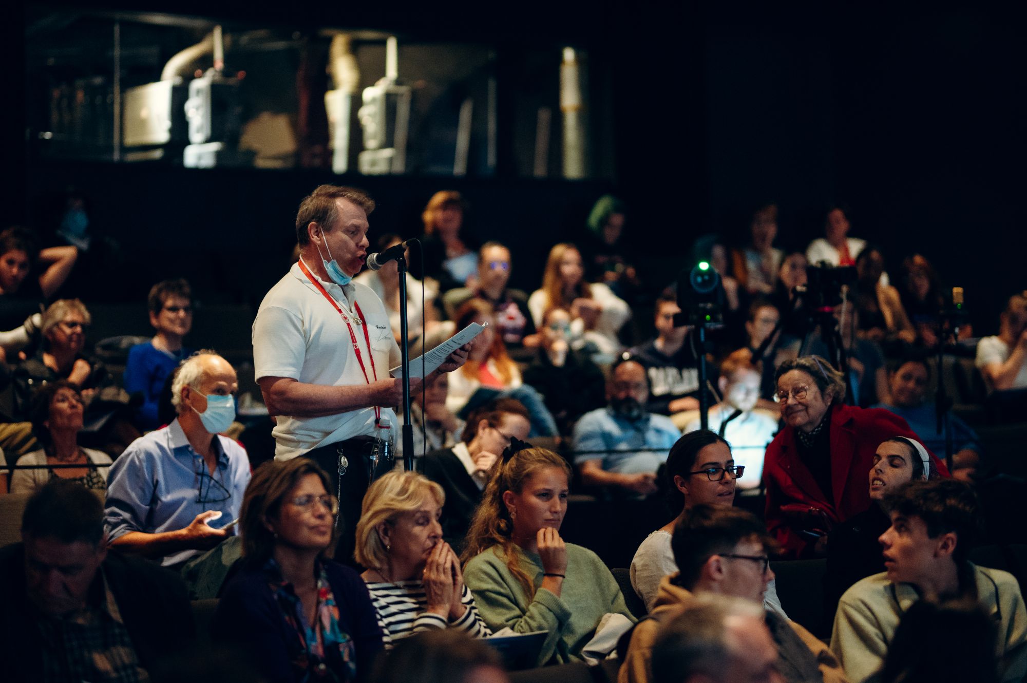 A man asking a question in a crowded room 